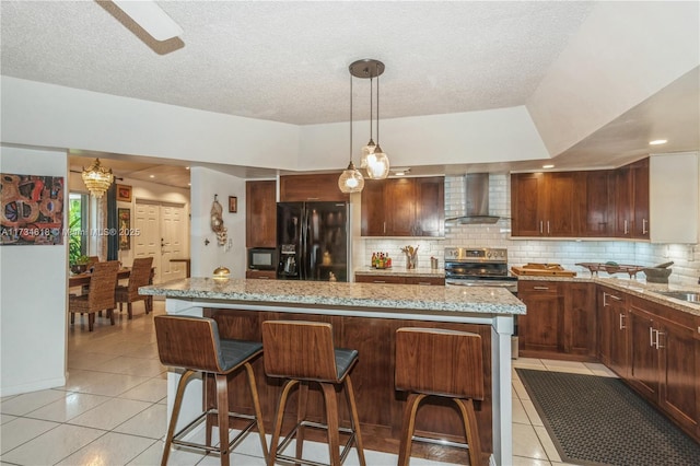 kitchen with wall chimney exhaust hood, black fridge, stainless steel electric range, light tile patterned floors, and a kitchen island