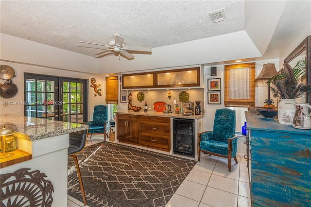 kitchen featuring tile patterned flooring, beverage cooler, a textured ceiling, and french doors