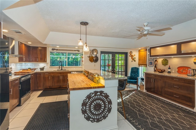 kitchen featuring sink, wooden counters, backsplash, a kitchen bar, and light tile patterned flooring