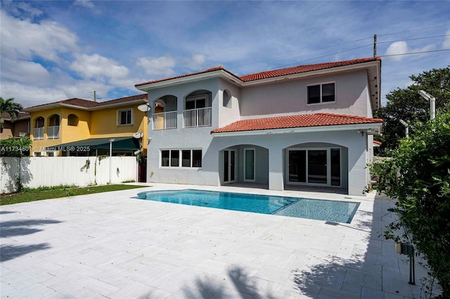 rear view of house with a fenced in pool and a patio area