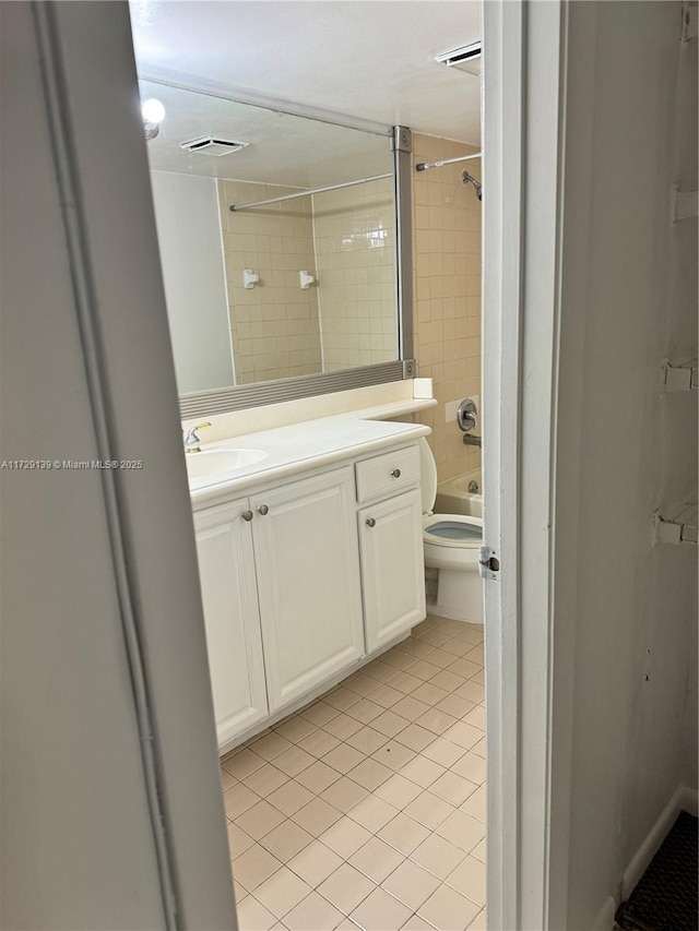 full bathroom featuring tiled shower / bath, vanity, toilet, and tile patterned flooring