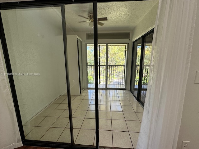 empty room with light tile patterned flooring, ceiling fan, and a textured ceiling