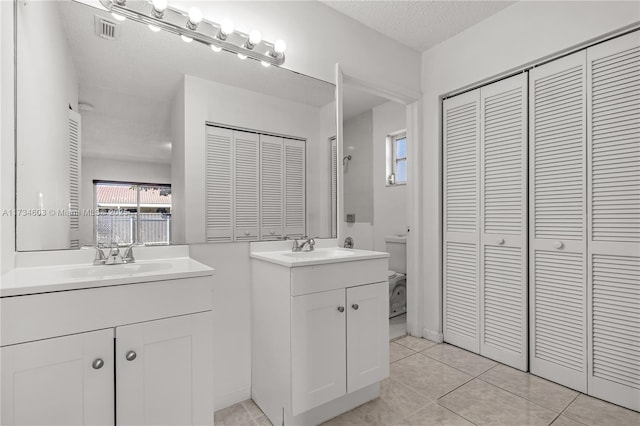 bathroom featuring tile patterned floors, vanity, toilet, and a textured ceiling