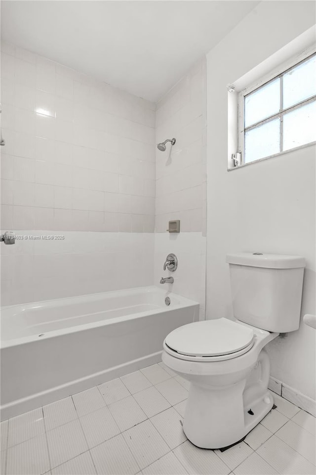 bathroom with tiled shower / bath combo, tile patterned floors, and toilet