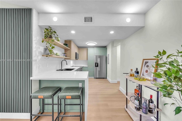 kitchen featuring open shelves, light countertops, visible vents, light wood-type flooring, and stainless steel fridge with ice dispenser