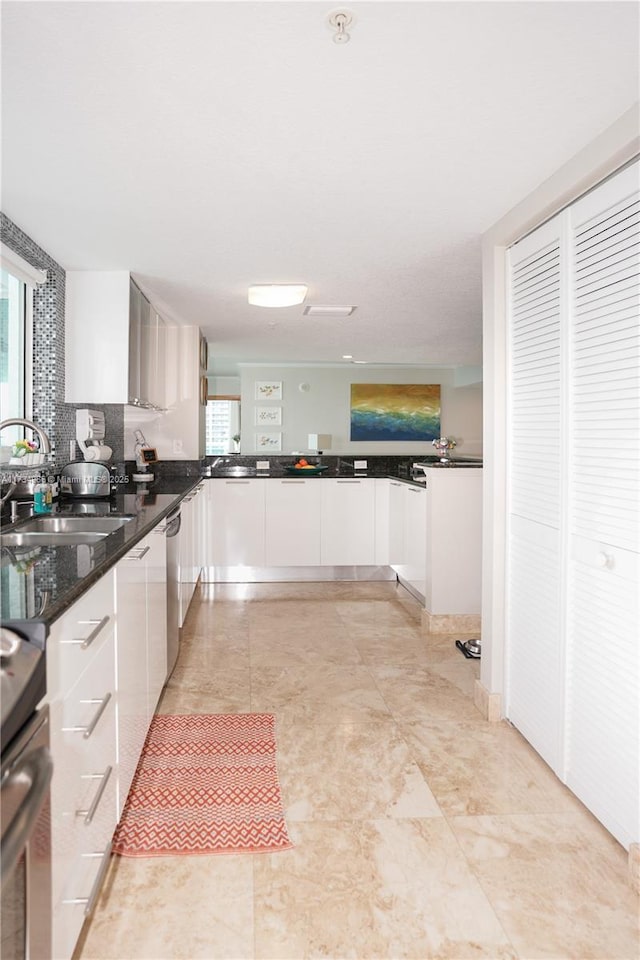 kitchen featuring white cabinetry, sink, dark stone countertops, stove, and stainless steel dishwasher