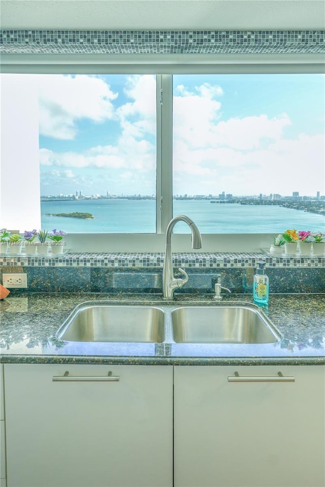 kitchen featuring a water view, sink, and white cabinets