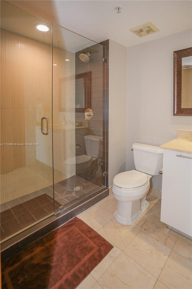 bathroom featuring vanity, a shower with shower door, and toilet