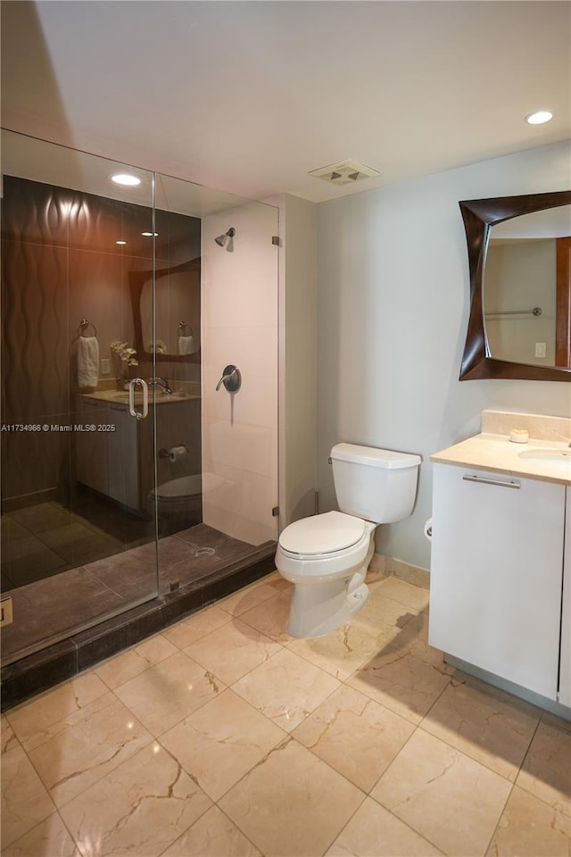 bathroom with vanity, a shower with door, and toilet