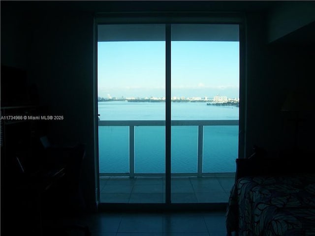 bedroom with multiple windows, tile patterned floors, and a water view