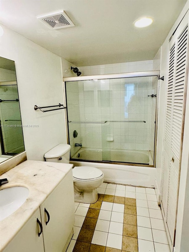 full bathroom featuring vanity, tile patterned floors, shower / bath combination with glass door, and toilet