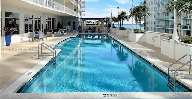 view of pool featuring a patio and a water view