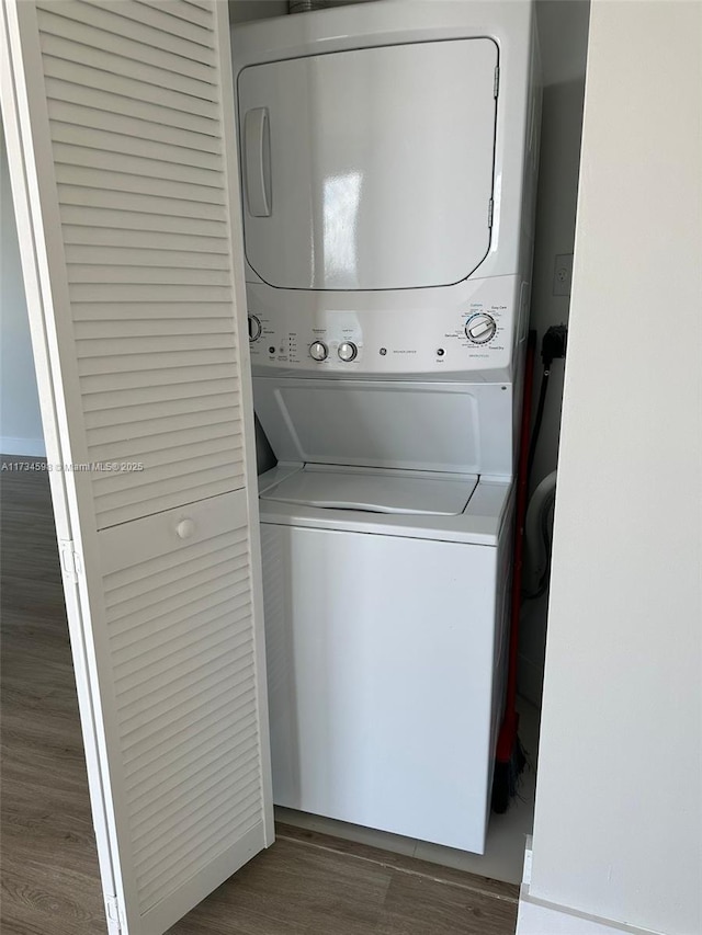 laundry area with stacked washing maching and dryer and dark hardwood / wood-style flooring