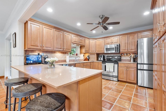 kitchen featuring sink, tasteful backsplash, a kitchen breakfast bar, ceiling fan, and stainless steel appliances