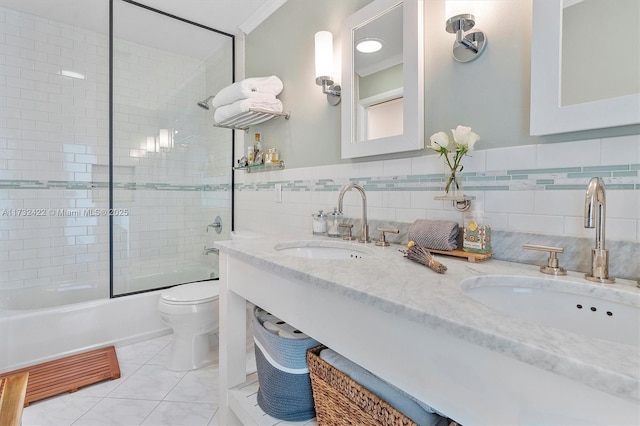 full bathroom featuring tile patterned floors, toilet, combined bath / shower with glass door, crown molding, and tile walls