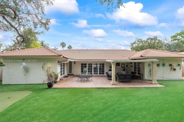 back of property featuring a patio, a yard, and french doors