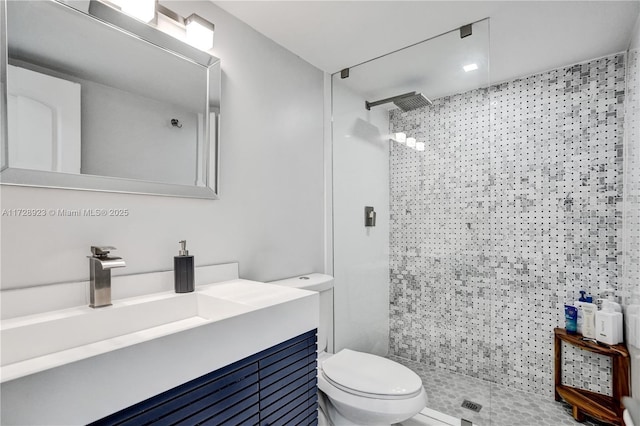 bathroom featuring vanity, a tile shower, and toilet