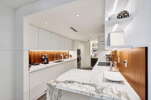 kitchen featuring wine cooler, sink, white cabinetry, kitchen peninsula, and black appliances