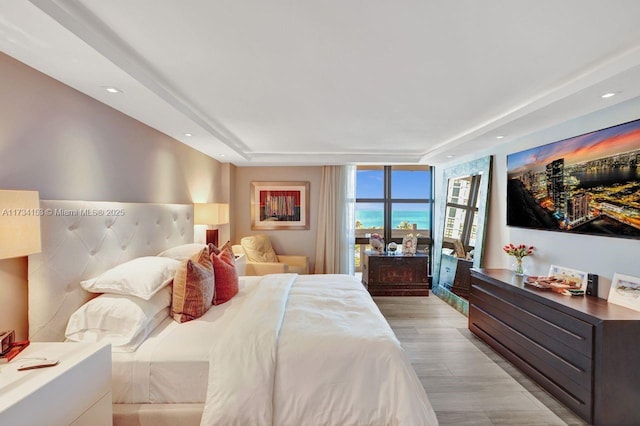 bedroom featuring a wall of windows and light hardwood / wood-style flooring