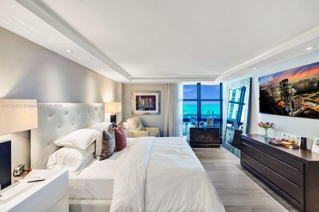 bedroom with a fireplace, expansive windows, and light wood-type flooring