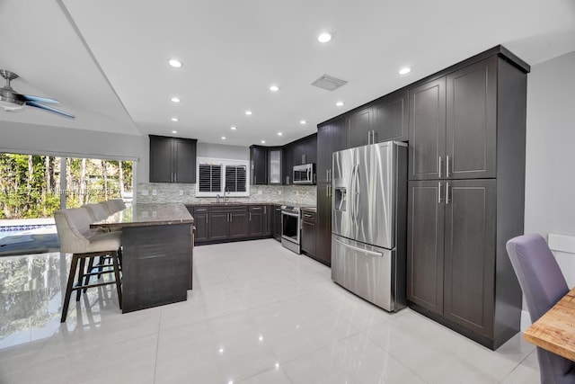 kitchen featuring sink, a breakfast bar, stone counters, stainless steel appliances, and decorative backsplash