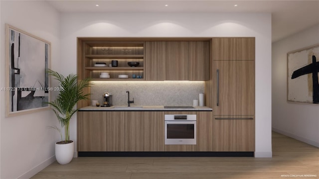 bar featuring black electric cooktop, oven, sink, and light wood-type flooring