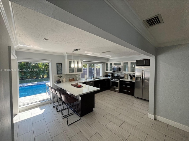 kitchen with appliances with stainless steel finishes, a breakfast bar, pendant lighting, sink, and kitchen peninsula