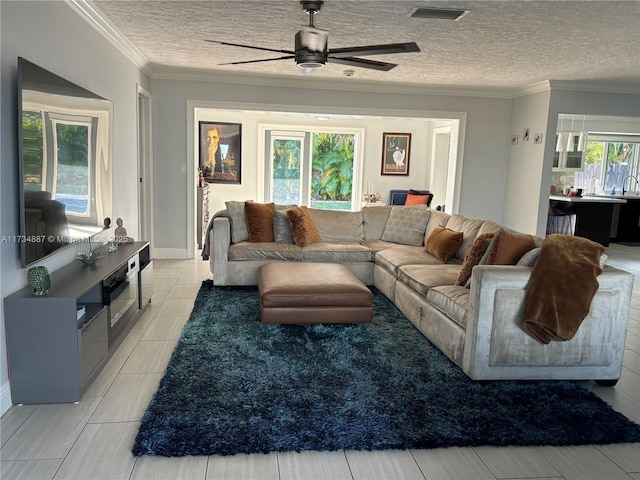 living room with ceiling fan, ornamental molding, and a textured ceiling