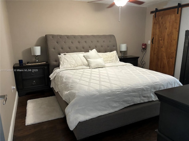 bedroom featuring dark hardwood / wood-style floors, a barn door, and ceiling fan