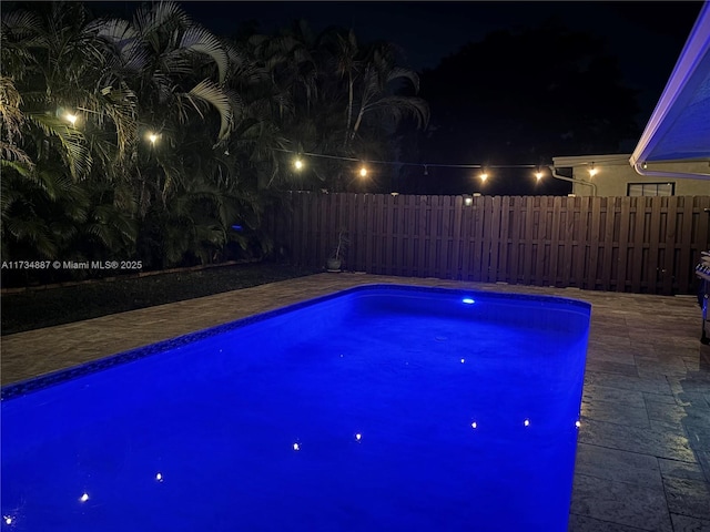 pool at night featuring a patio