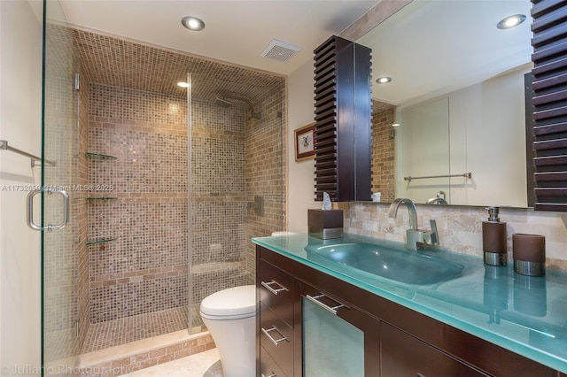 bathroom featuring vanity, toilet, a shower with shower door, and backsplash