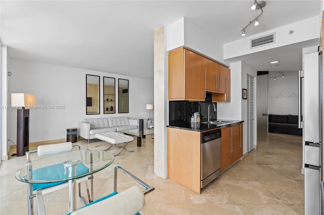 kitchen featuring tasteful backsplash, rail lighting, sink, fridge, and stainless steel dishwasher