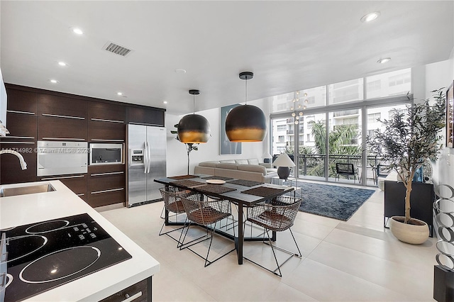 kitchen featuring pendant lighting, sink, light tile patterned floors, built in appliances, and dark brown cabinetry