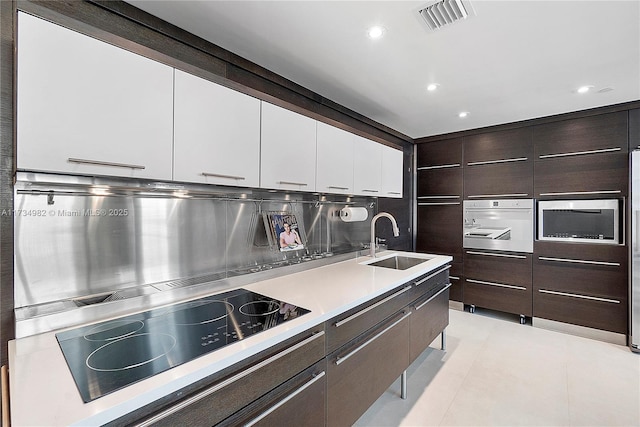 kitchen with white cabinetry, sink, backsplash, oven, and black electric cooktop