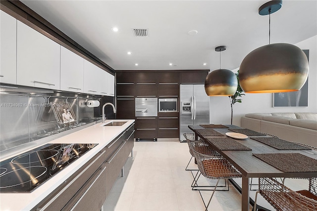 kitchen featuring sink, white cabinetry, dark brown cabinets, hanging light fixtures, and appliances with stainless steel finishes