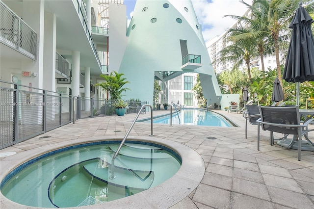 view of swimming pool featuring a community hot tub and a patio