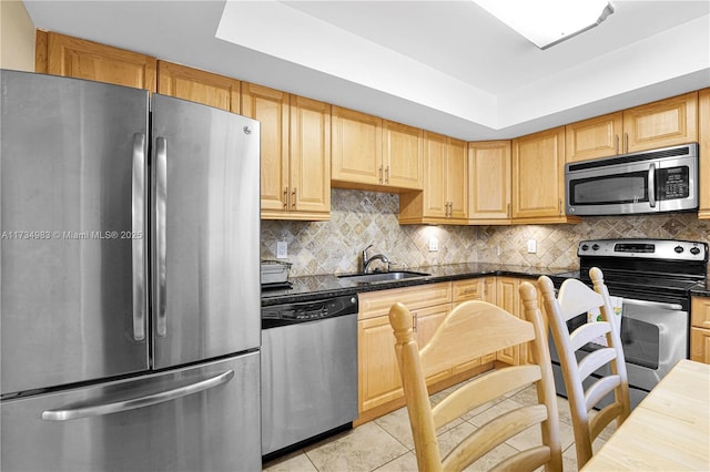 kitchen featuring appliances with stainless steel finishes, light brown cabinetry, sink, backsplash, and light tile patterned floors