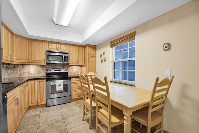 kitchen featuring light tile patterned floors, stainless steel appliances, light brown cabinetry, decorative backsplash, and a raised ceiling