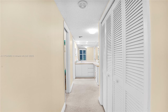 corridor with sink and a textured ceiling