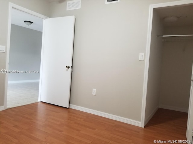 unfurnished bedroom featuring a closet, a spacious closet, and light hardwood / wood-style flooring