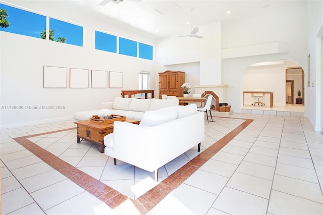 living room featuring a towering ceiling, ceiling fan, and light tile patterned flooring