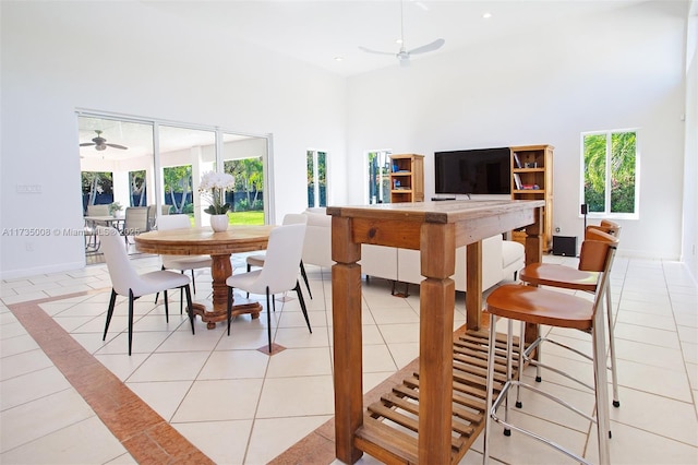 dining area with plenty of natural light, a towering ceiling, light tile patterned floors, and ceiling fan