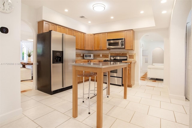 kitchen featuring light tile patterned flooring, stainless steel appliances, and decorative backsplash