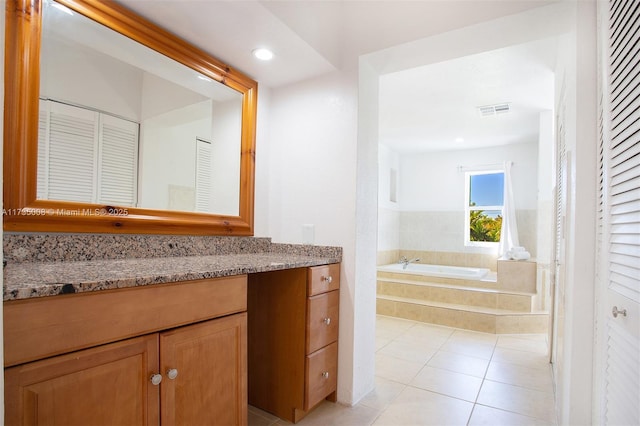 bathroom with tile patterned flooring, vanity, and a relaxing tiled tub