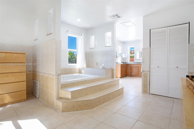 bathroom featuring tile patterned flooring, vanity, and a relaxing tiled tub