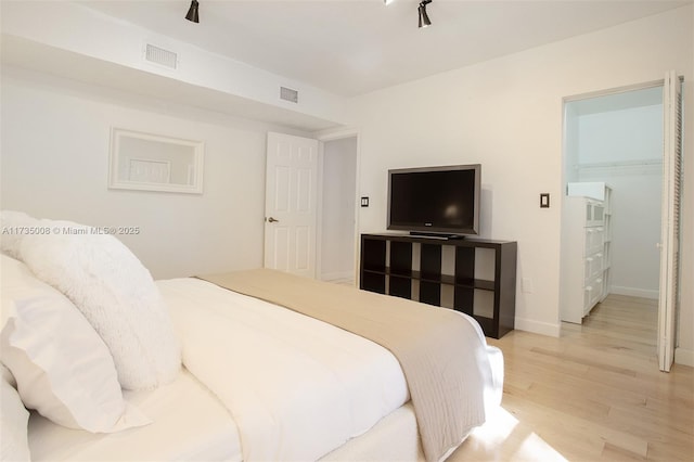 bedroom with hardwood / wood-style floors and a spacious closet