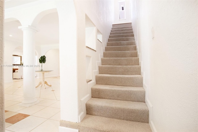 stairway with decorative columns and tile patterned floors