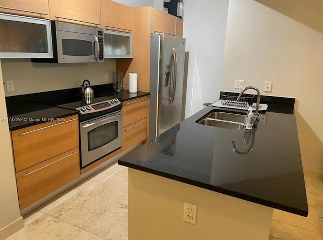 kitchen with sink, dark stone counters, and appliances with stainless steel finishes