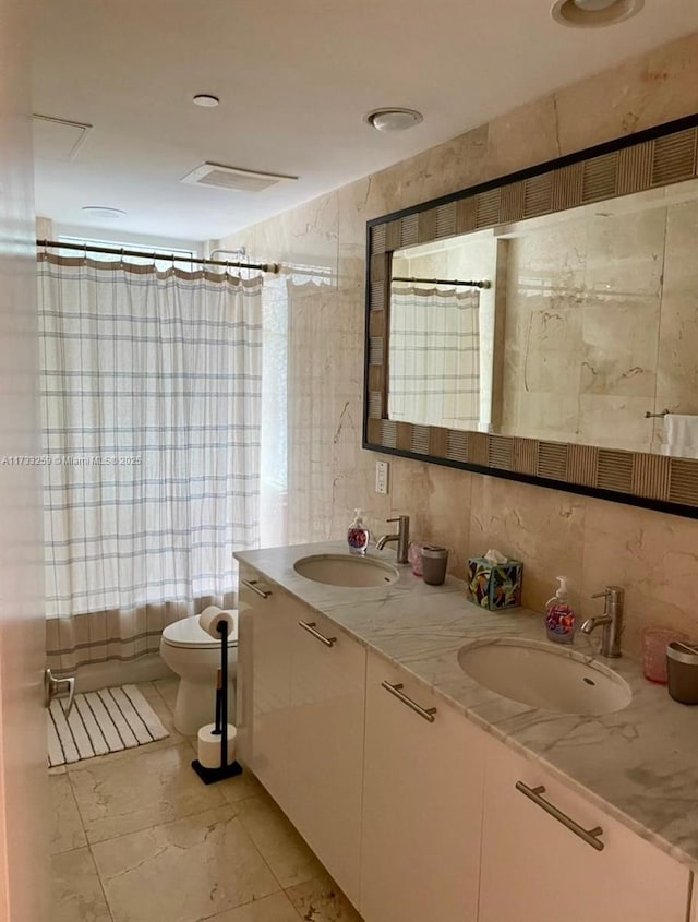 full bathroom featuring vanity, tile walls, shower / tub combo with curtain, and toilet