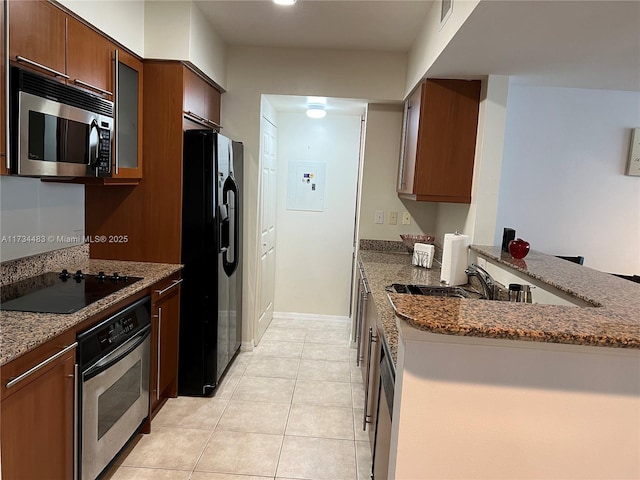 kitchen with light tile patterned floors, electric panel, black appliances, stone countertops, and kitchen peninsula